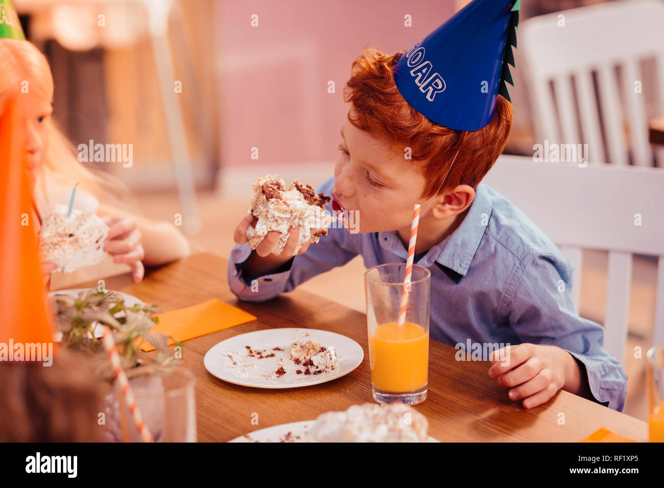 Positive delighted boy eating pastry with cream Stock Photo