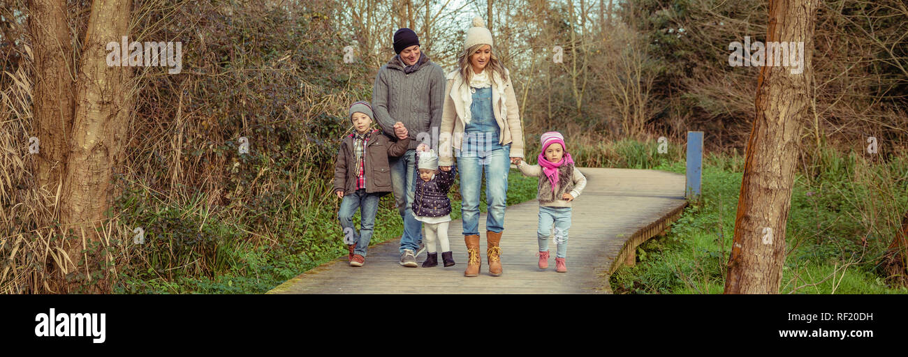 Happy family walking together holding hands in the forest Stock Photo