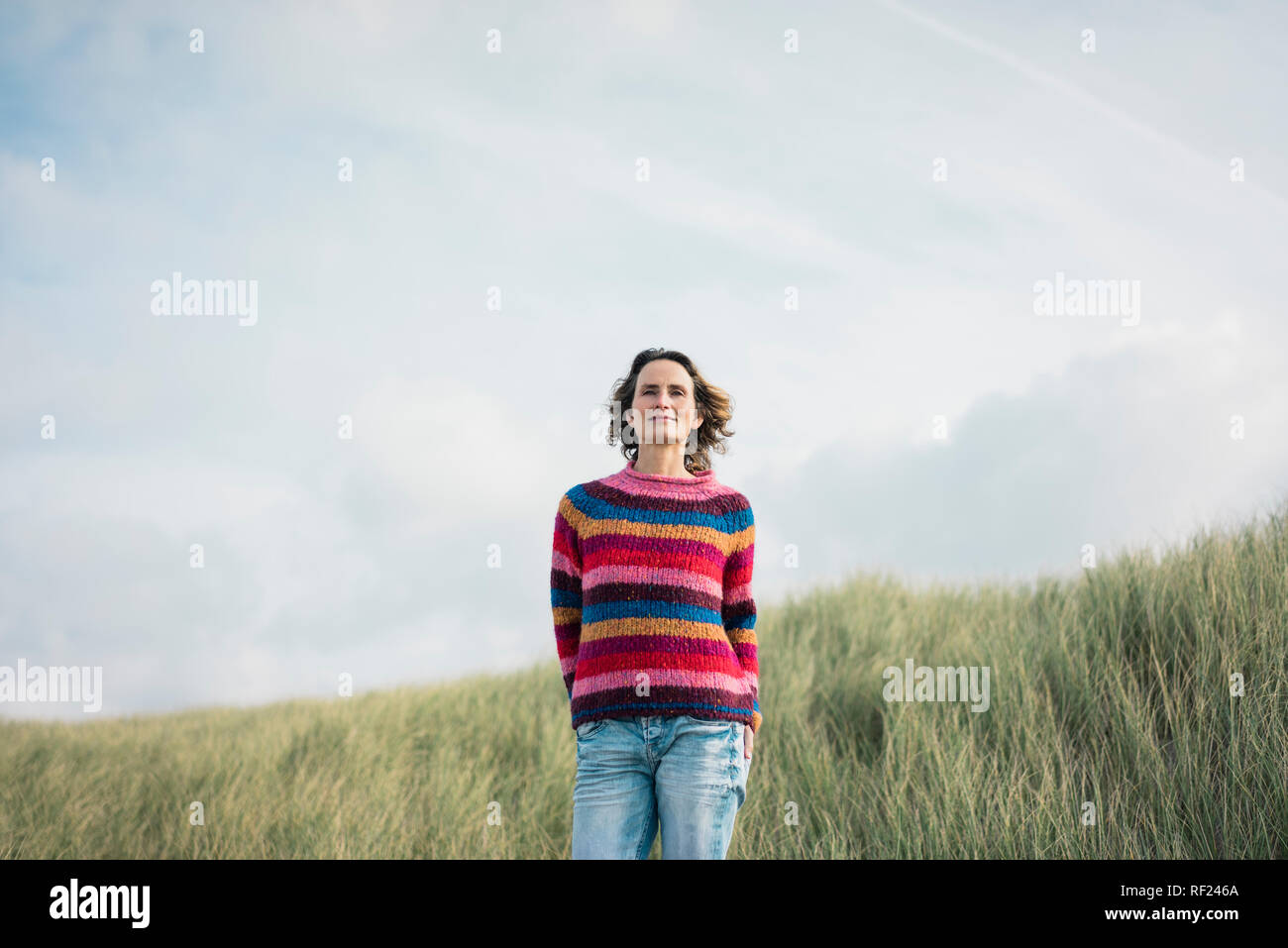 Content woman standing in the dunes, smiling Stock Photo