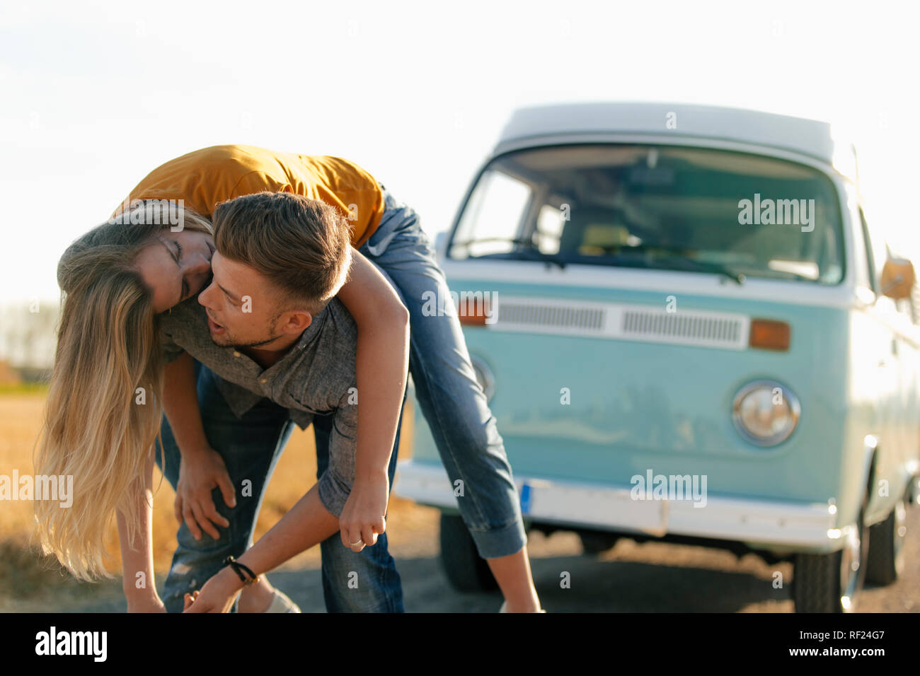 Playful young couple at camper van in rural landscape Stock Photo