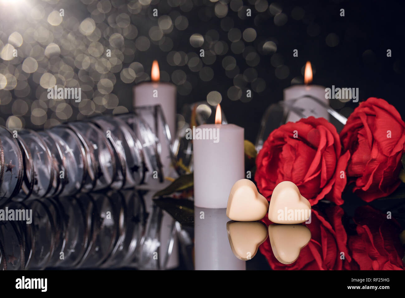 Valentines day greeting card with red roses, candles and heart shaped chocolate on black background Stock Photo