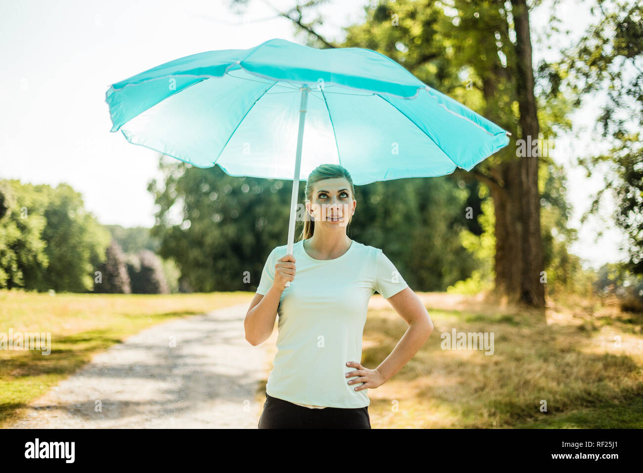 Sportive young woman standing in a park holding sunshade Stock Photo