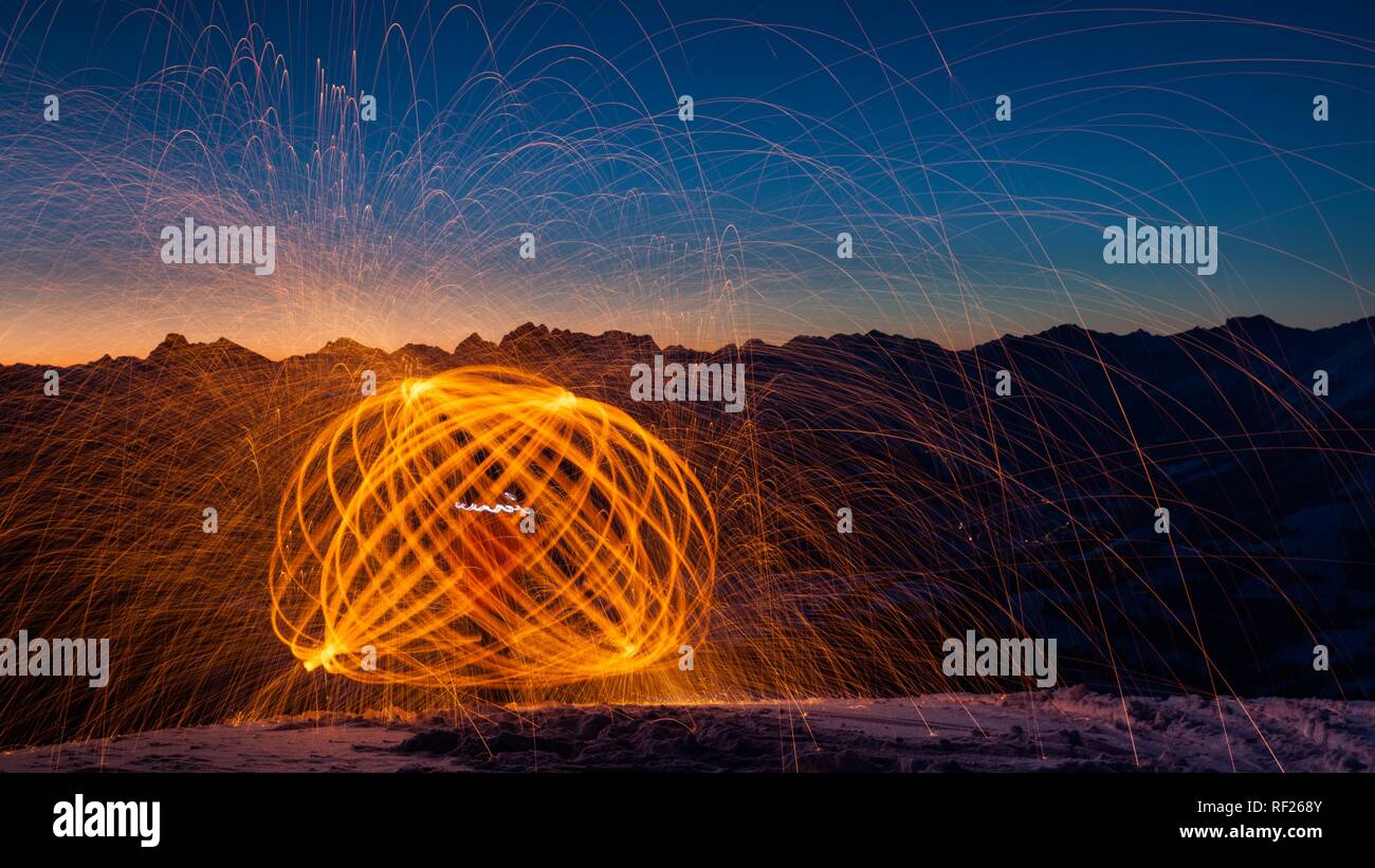 Flying sparks, traces of light, light painting on mountain peaks in front of sunrise, Wertacher Hörnle Stock Photo