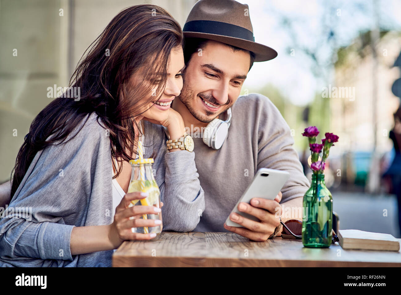 Happy young couple looking at cell phone at outdoors cafe Stock Photo