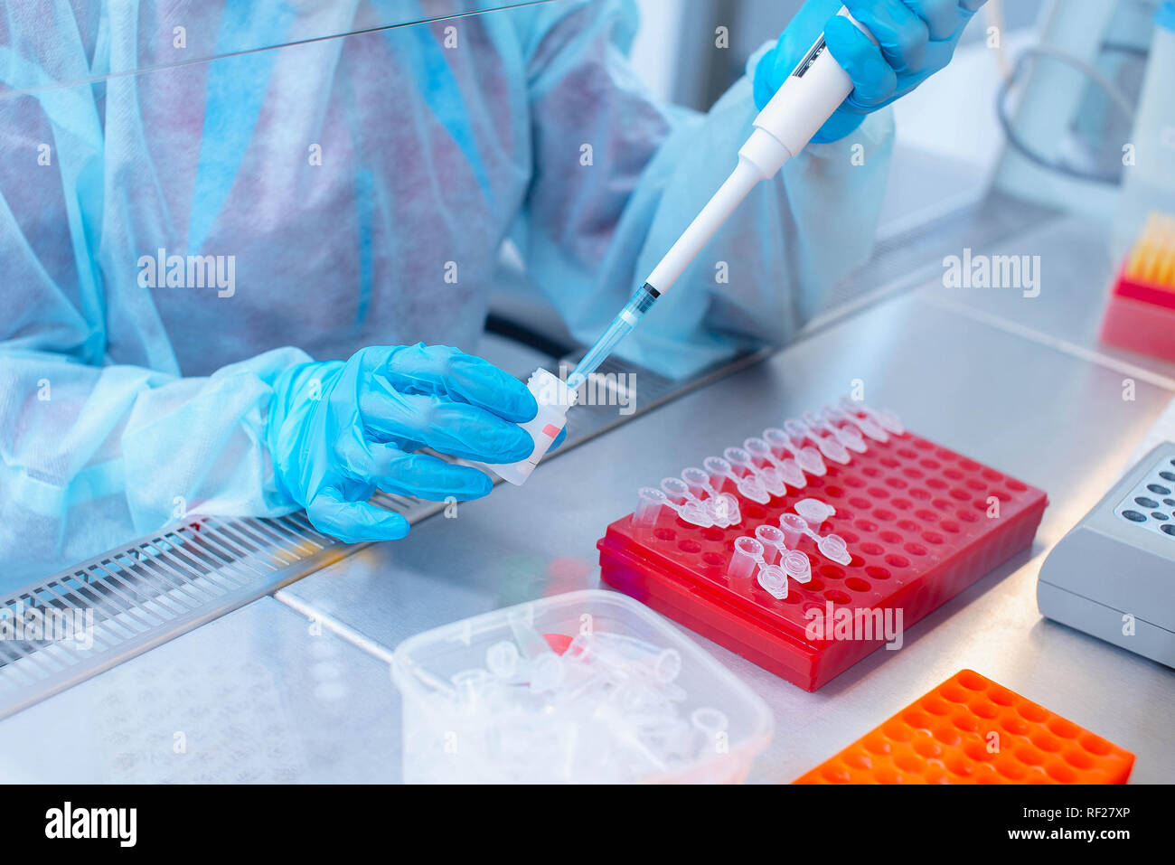 Dna test in the lab. a laboratory technician with a dispenser in his hands is conducting dna analysis in a sterile laboratory behind glass. Stock Photo