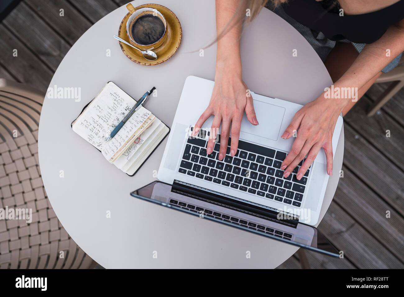 Young woman sitting outdoors working on laptop, top view Stock Photo