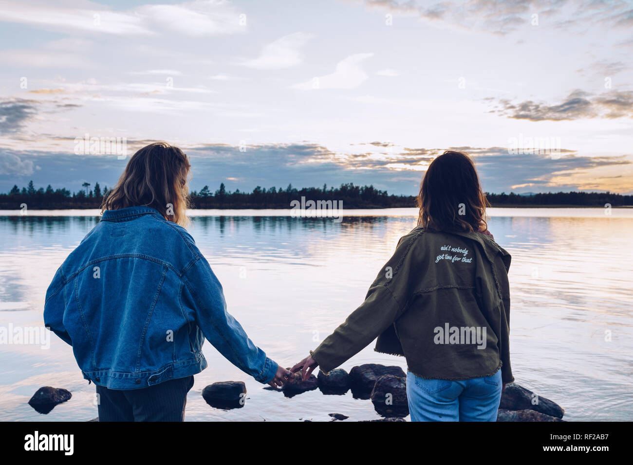 Girl friends looking at Lake Inari,Finland,  holding hands Stock Photo