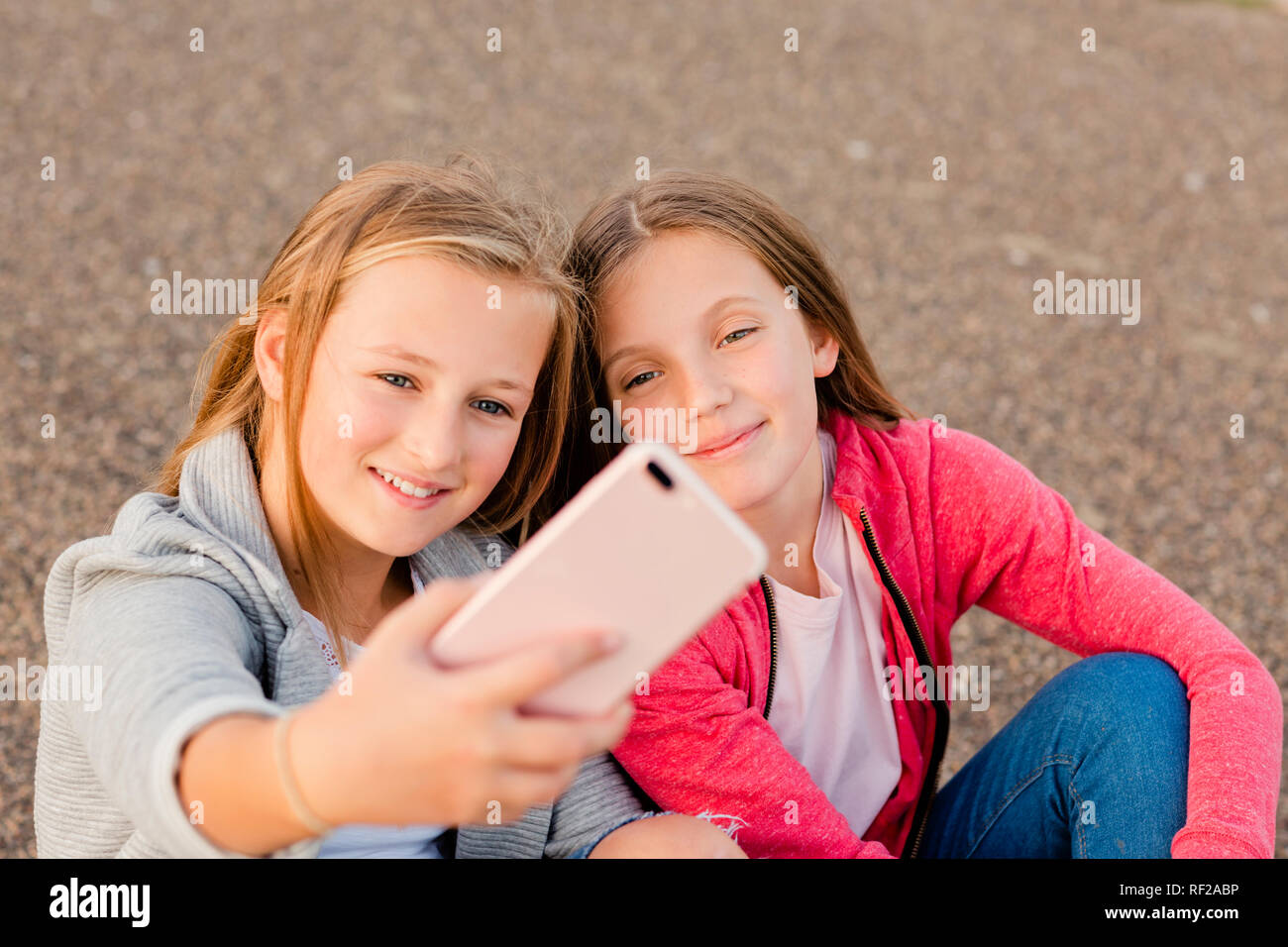 Portrait of two smiling girls taking selfie with smartphone Stock Photo
