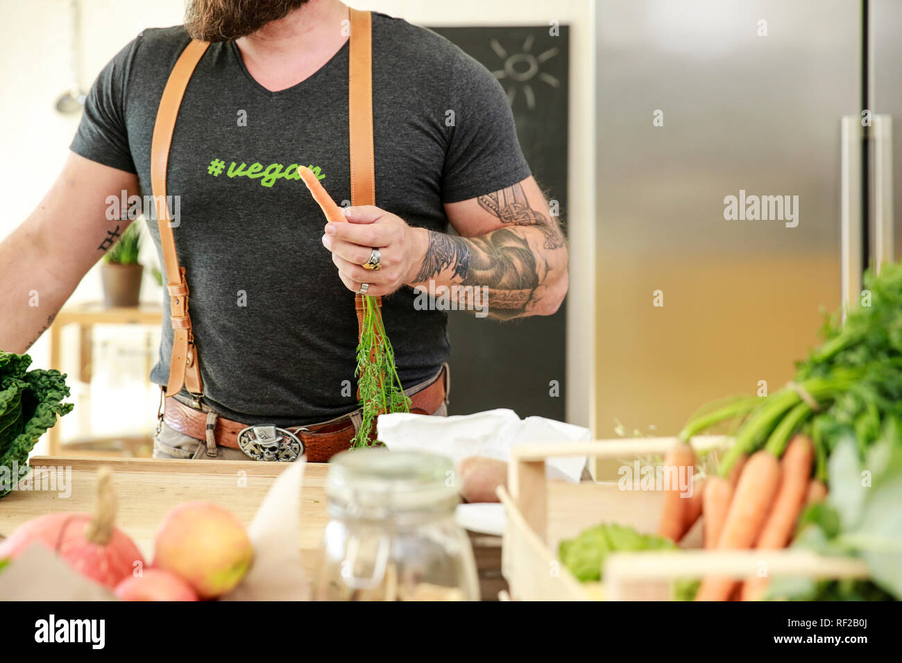 Vegan man holding carrot in his kitchen Stock Photo - Alamy