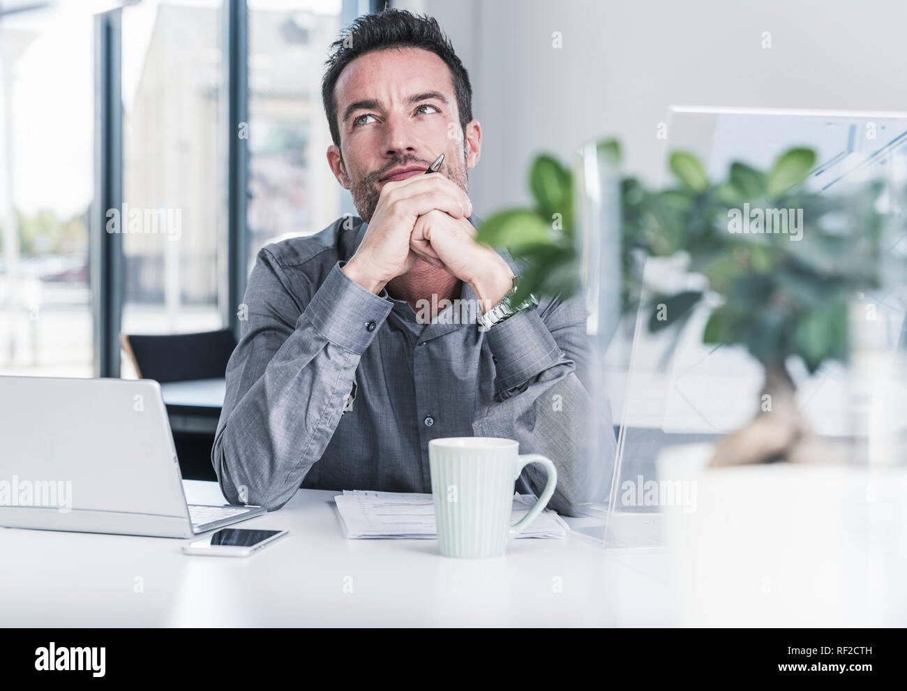 Businessman sitting in office, thinking Stock Photo