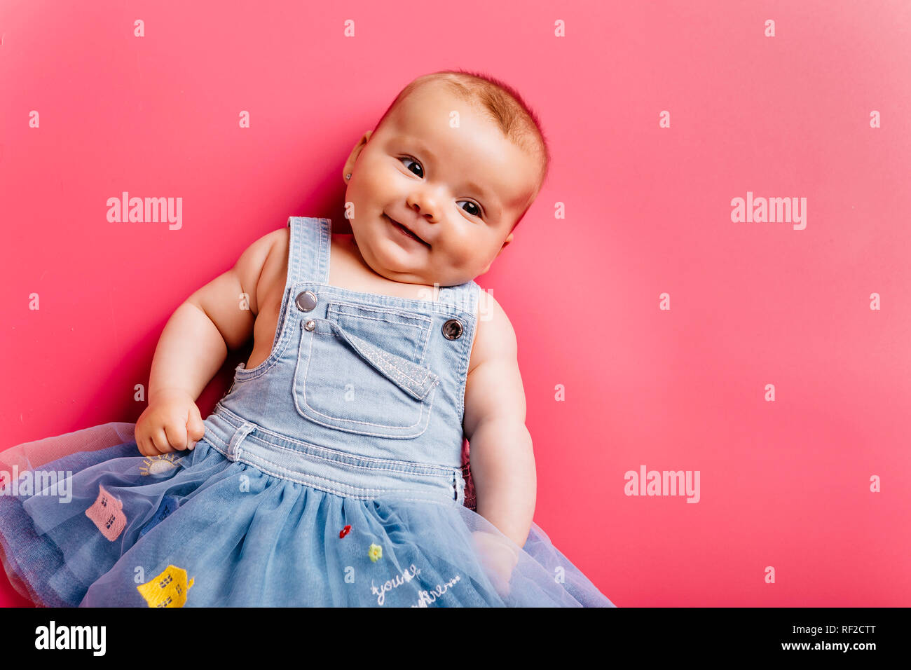 Portrait of smiling baby girl lying on pink background Stock Photo - Alamy