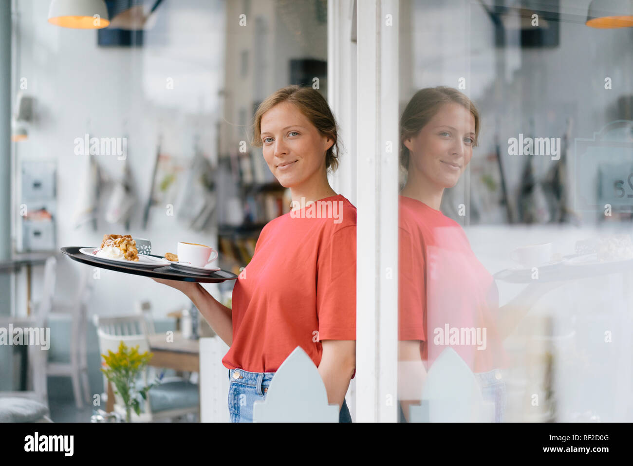 Portrait of smiling young woman serving coffee and cake in a cafe Stock Photo