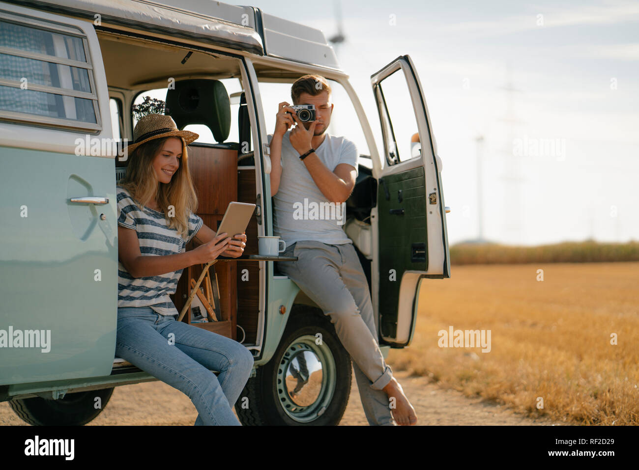 Young couple with tablet and camera at camper van in rural landscape Stock Photo