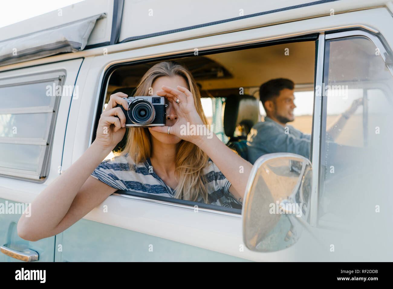 Woman taking picture out of window of a camper van with man driving Stock Photo