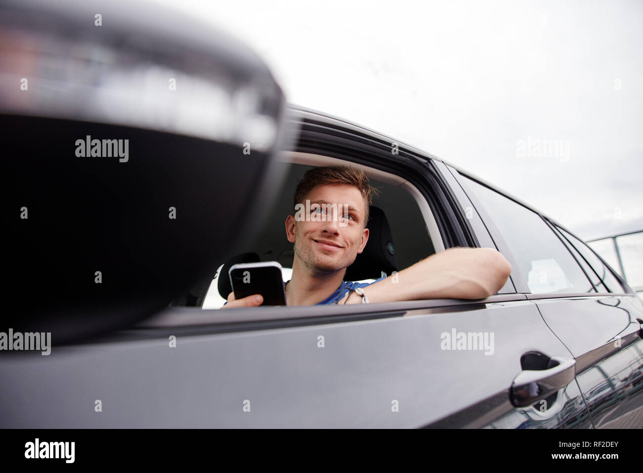 Smiling young man with cell phone in a car Stock Photo