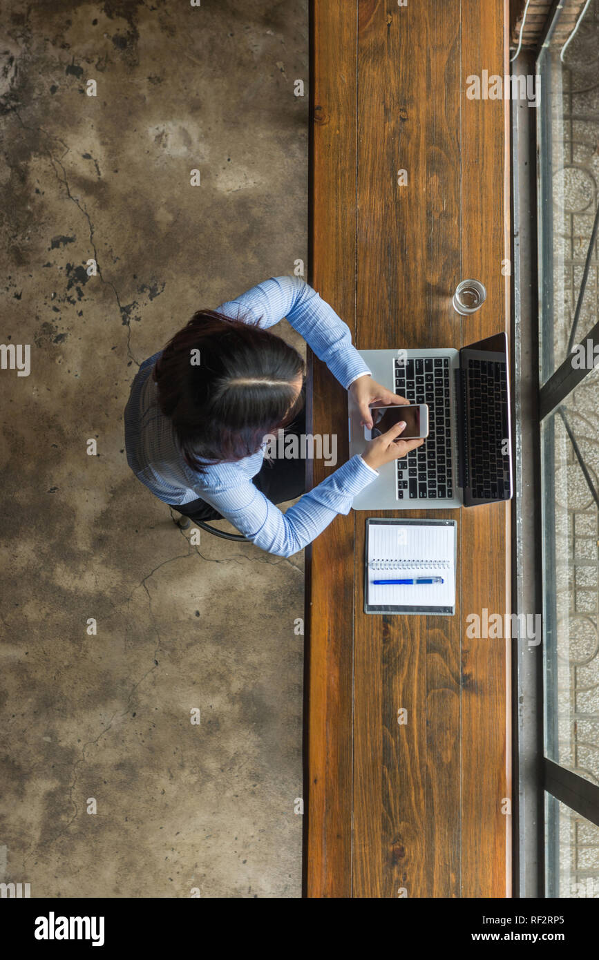 Young Asian woman using smartphone for work Stock Photo