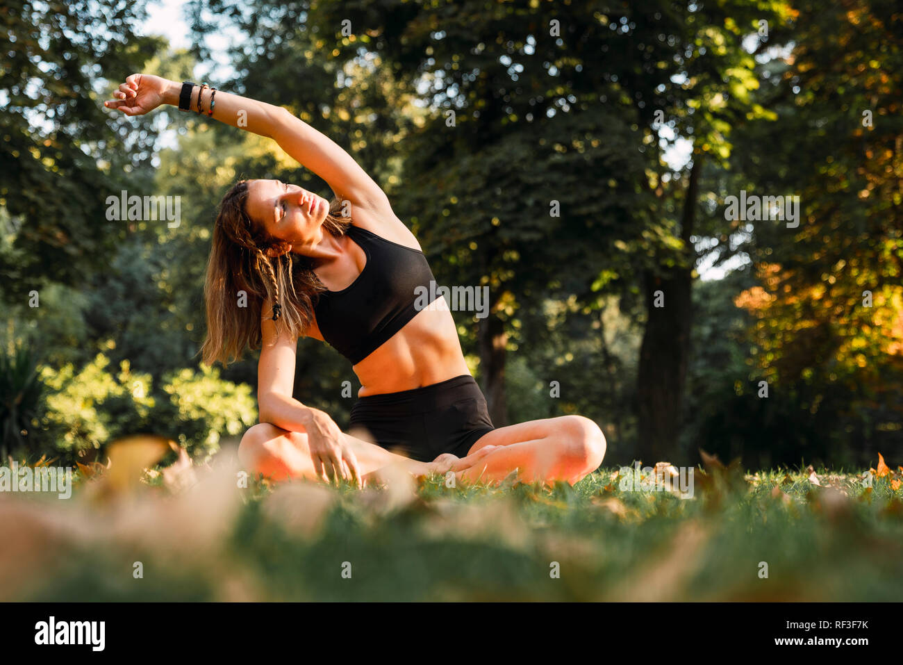 Fit young woman practicing yoga in a park Stock Photo