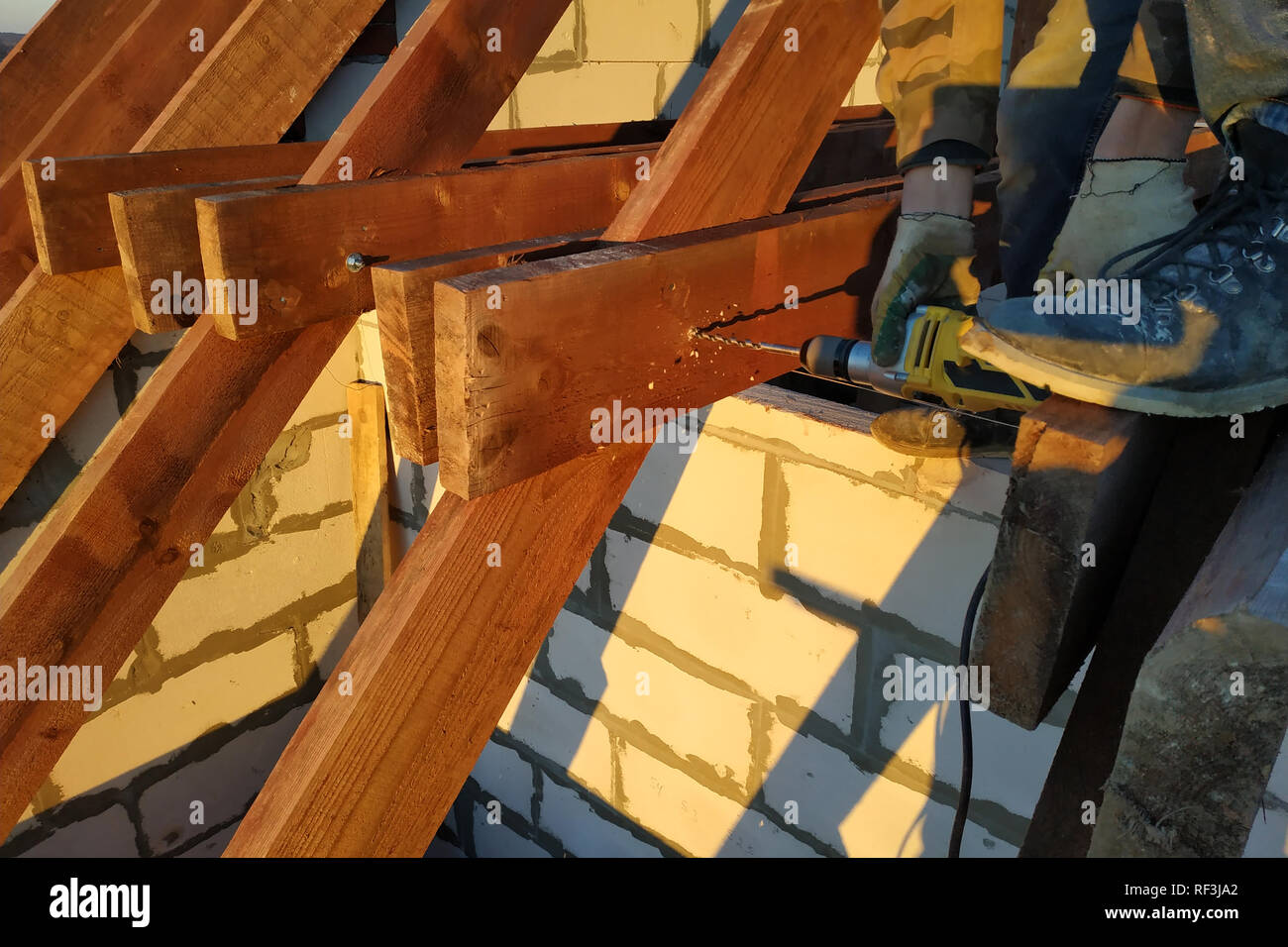 The worker uses a drill in the construction of the roof 2019 Stock Photo