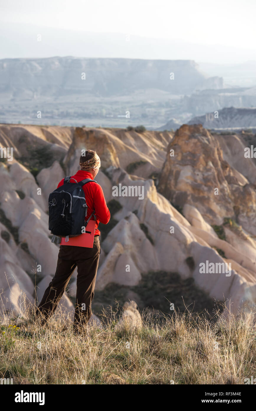 Amazing day in Cappadocia mountains, Turkey. Photographer in red jacket taking photo of amazing hills. Landscape photography Stock Photo