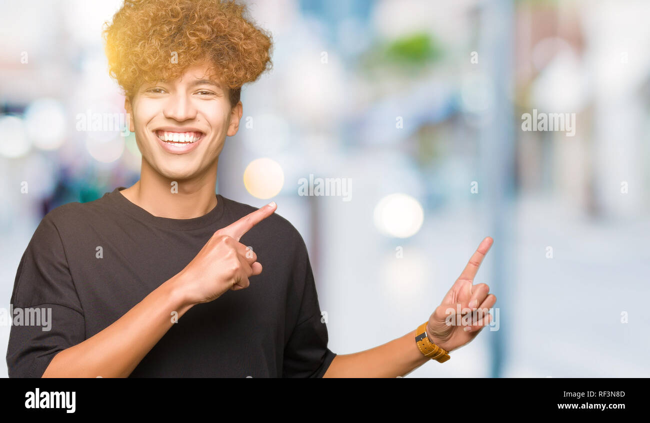 Young handsome man with afro hair wearing black t-shirt smiling and ...