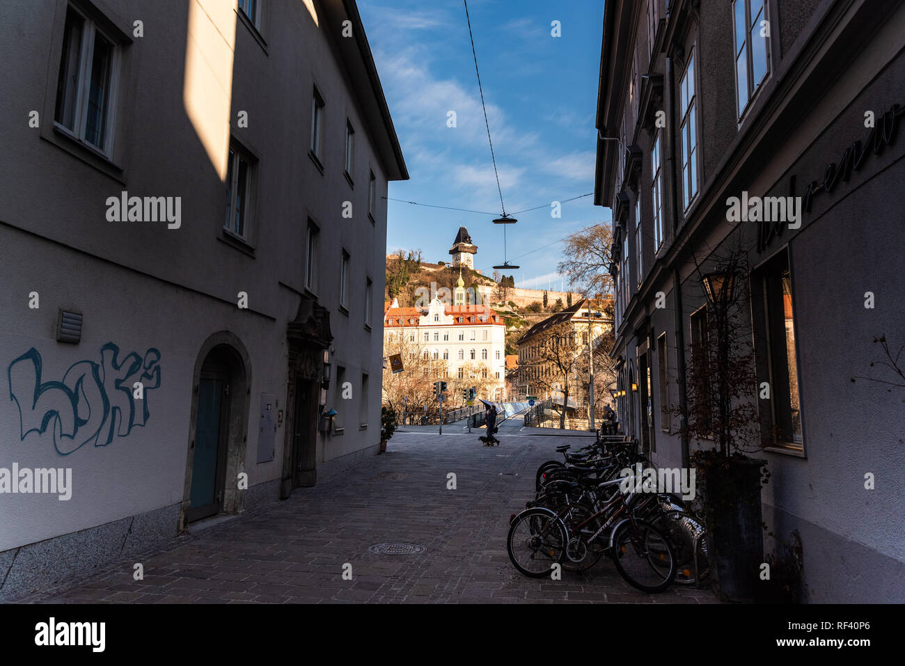 Graz, Styria / Austria - 20.01.2019: View at street leading to clock tower, people walking by in winter sun Travel destination Stock Photo