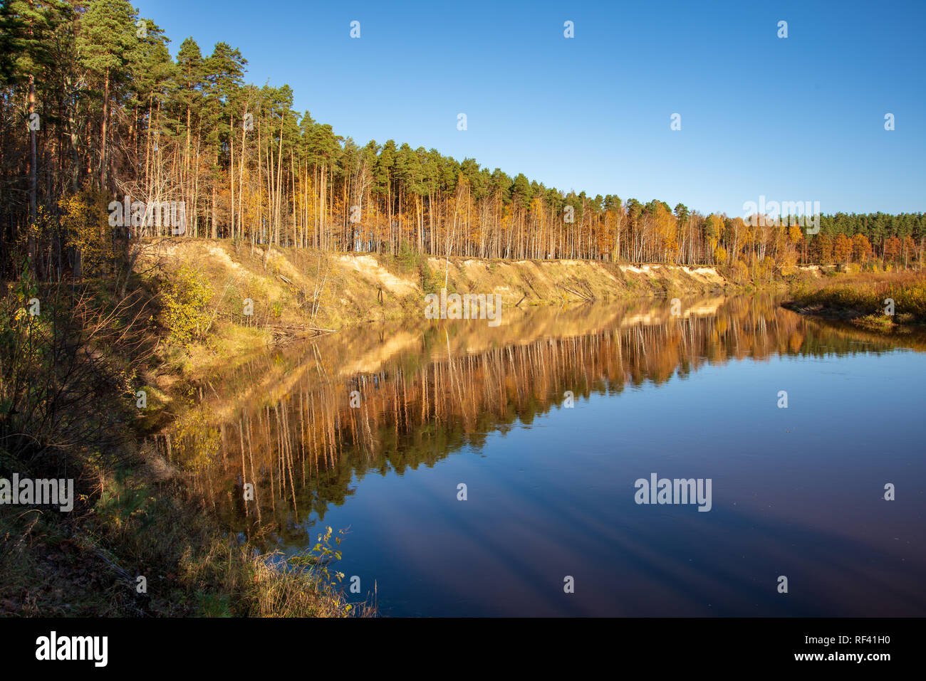 Fall In Riga blue sky and clouds reflecting in calm water of river Gauja in latvia ...