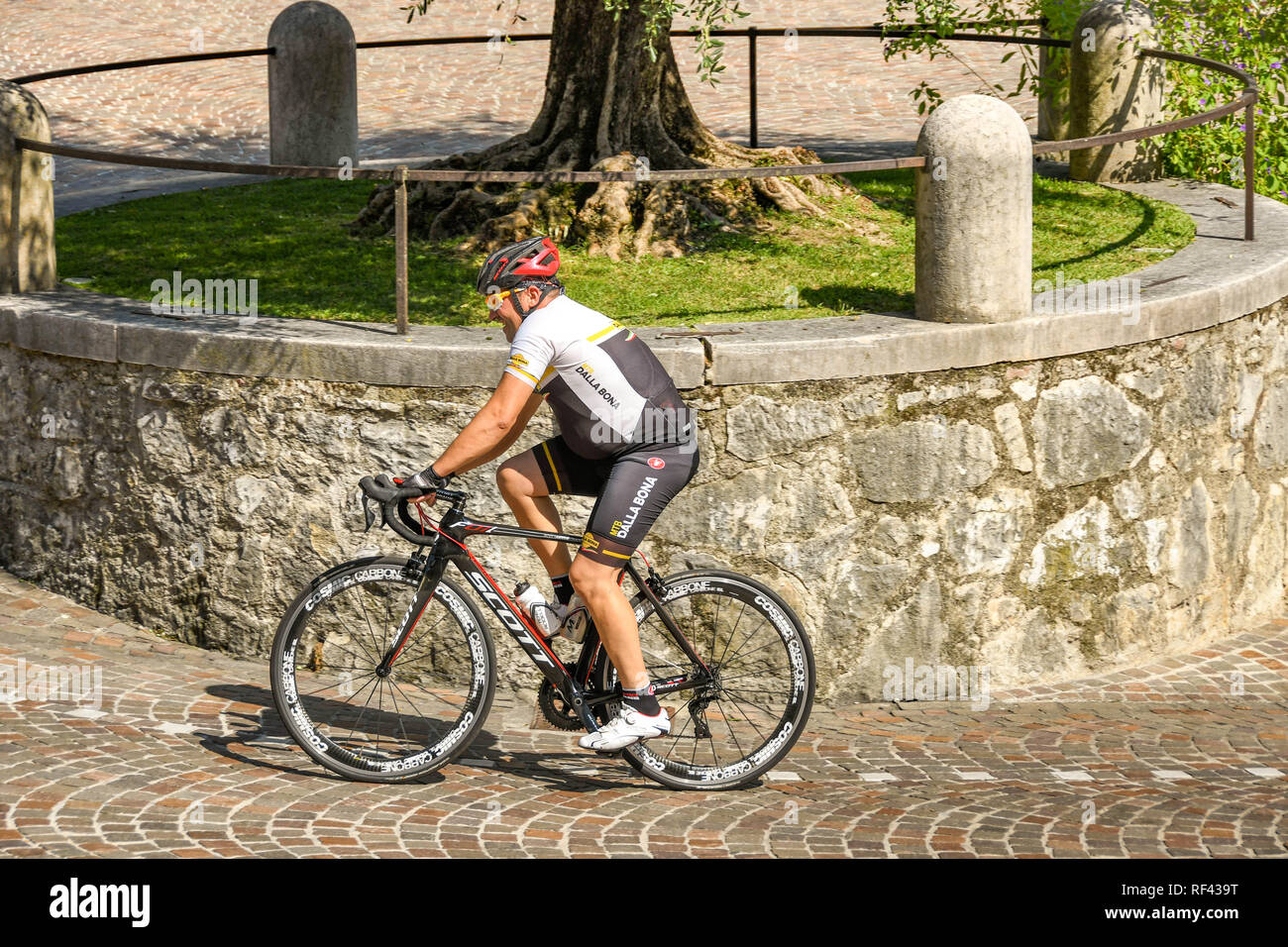 GARDONE RIVIERA, ITALY - SEPTEMBER 2018: Cyclist pedalling up the steep hill outside the Vittoriale degli Italiani gardens in Gardone Riviera. Stock Photo