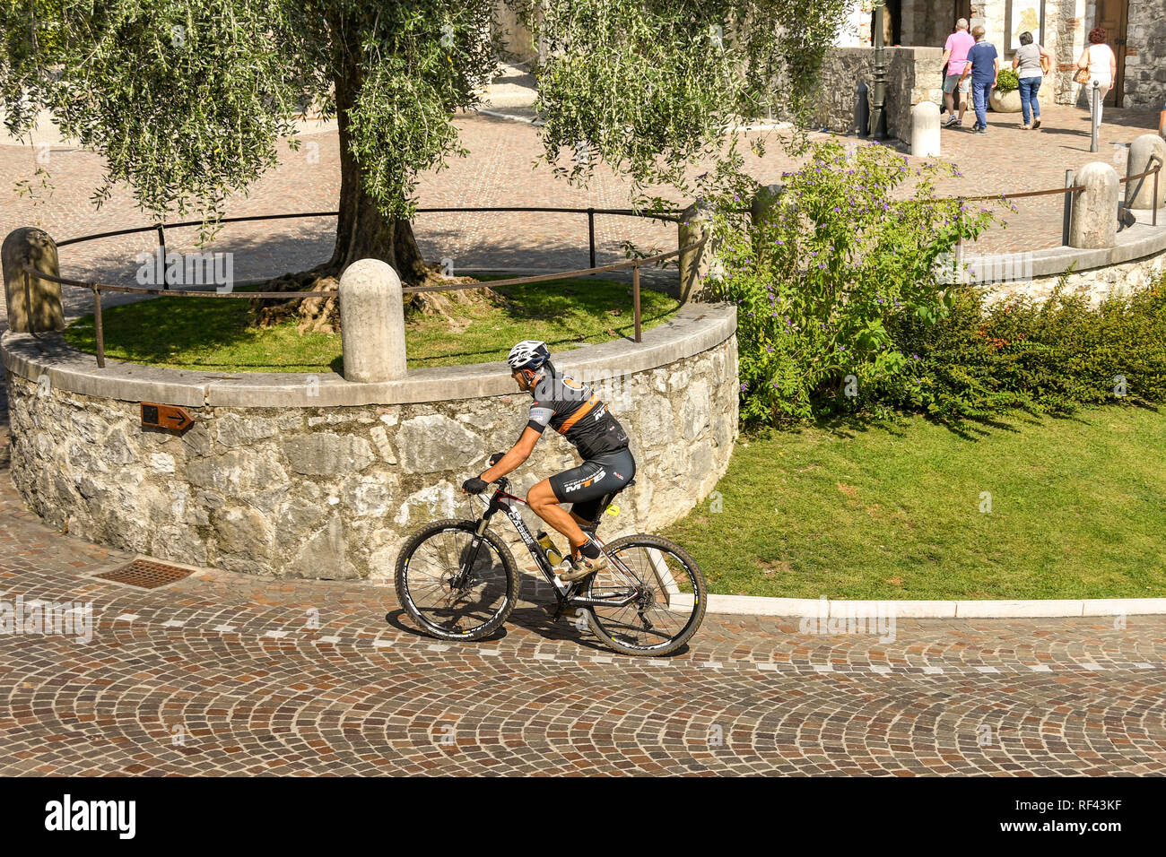 GARDONE RIVIERA, ITALY - SEPTEMBER 2018: Cyclist pedalling up the steep hil outside the Vittoriale degli Italiani gardens in Gardone Riviera. Stock Photo