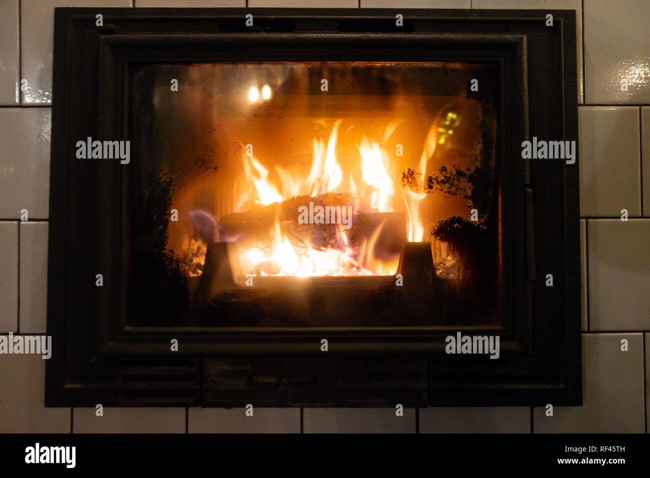 A log burning in a wood burner provides heat for the room. Stock Photo
