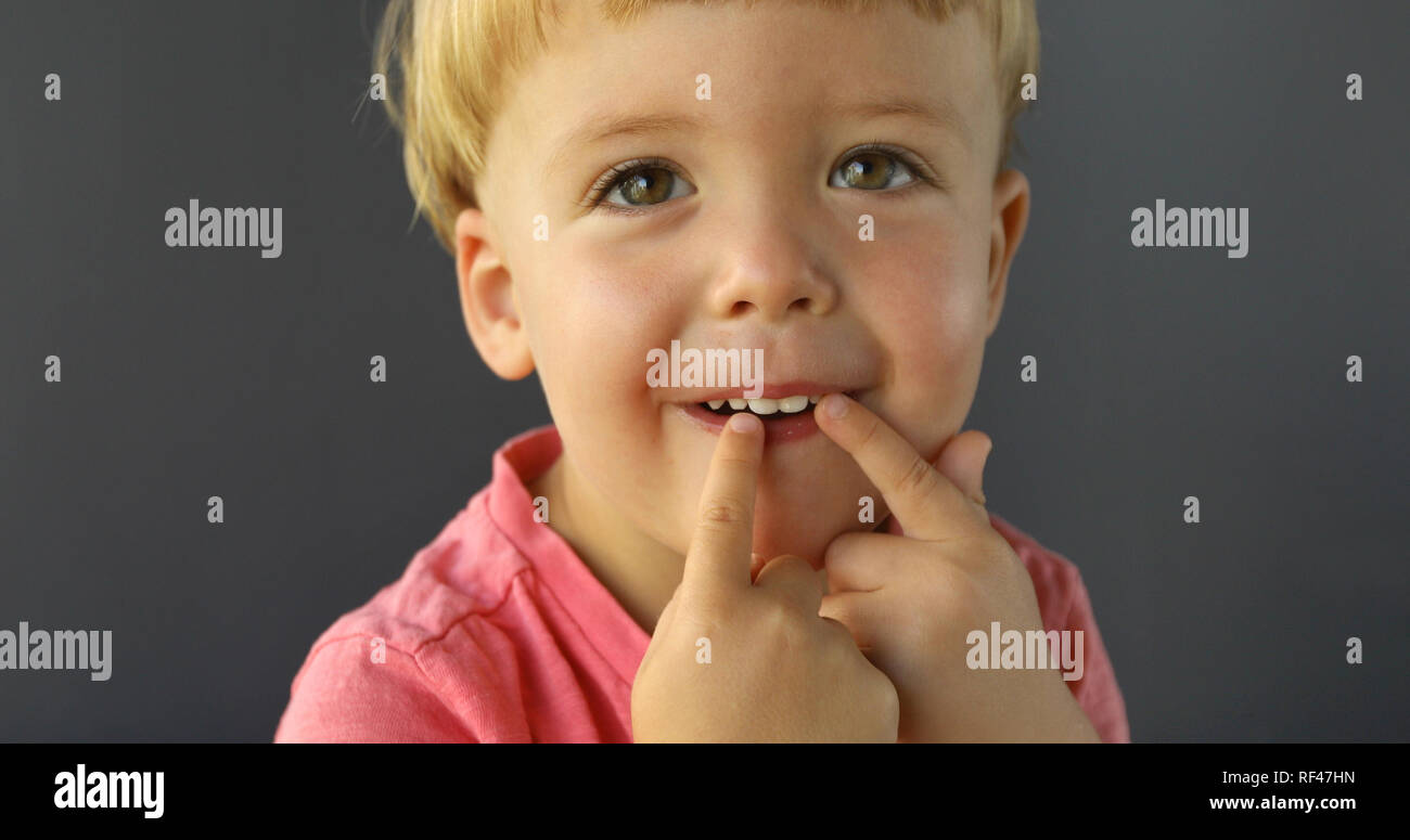 Boy points his fingers of both hands on his teeth Stock Photo