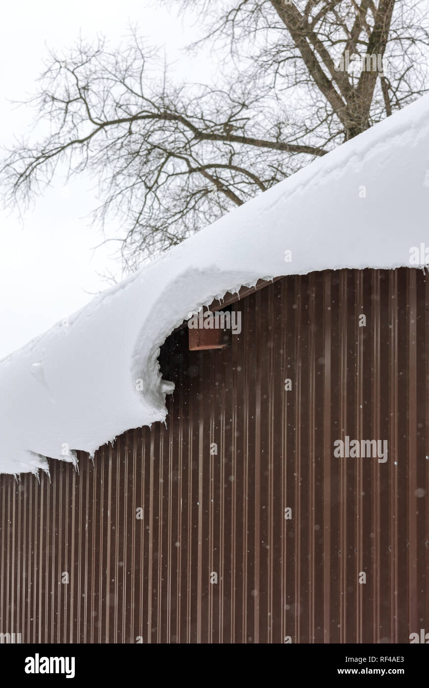 House Roof With Snow Cornice And Icicles At Winter Day Stock Photo