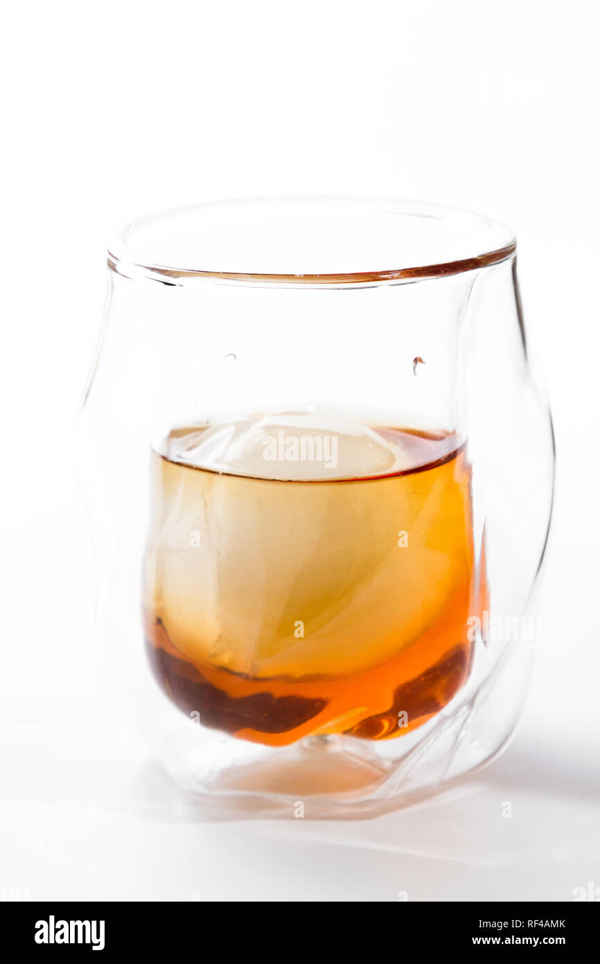 Bourbon served in a double walled whisky glass served with an ice sphere over a white background Stock Photo