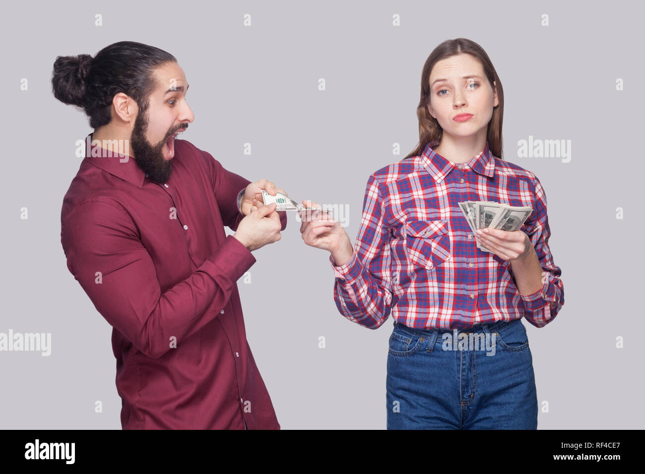 Portrait of rich serious woman with fan of money, sharing with amazed or surprised hungry man. standing and looking at camera like a boss. indoor stud Stock Photo