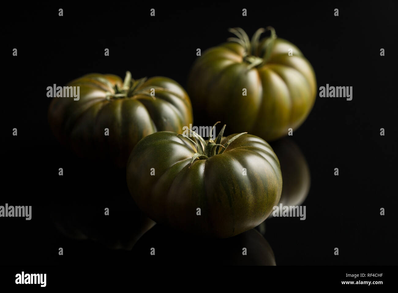 Dark brandywine tomatoes on black background. Stock Photo