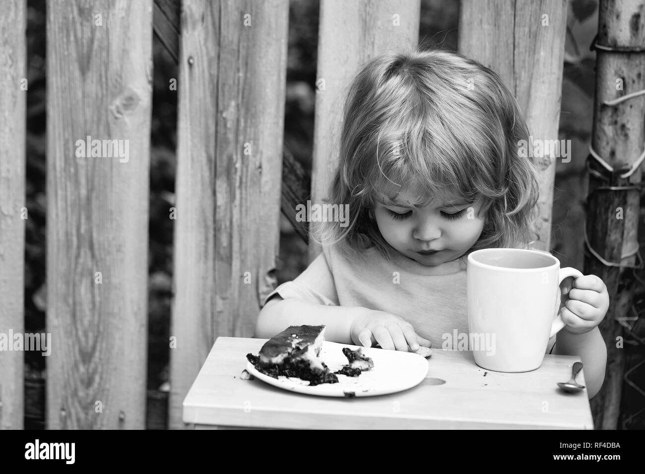 small boy eating pie near wooden fence Stock Photo
