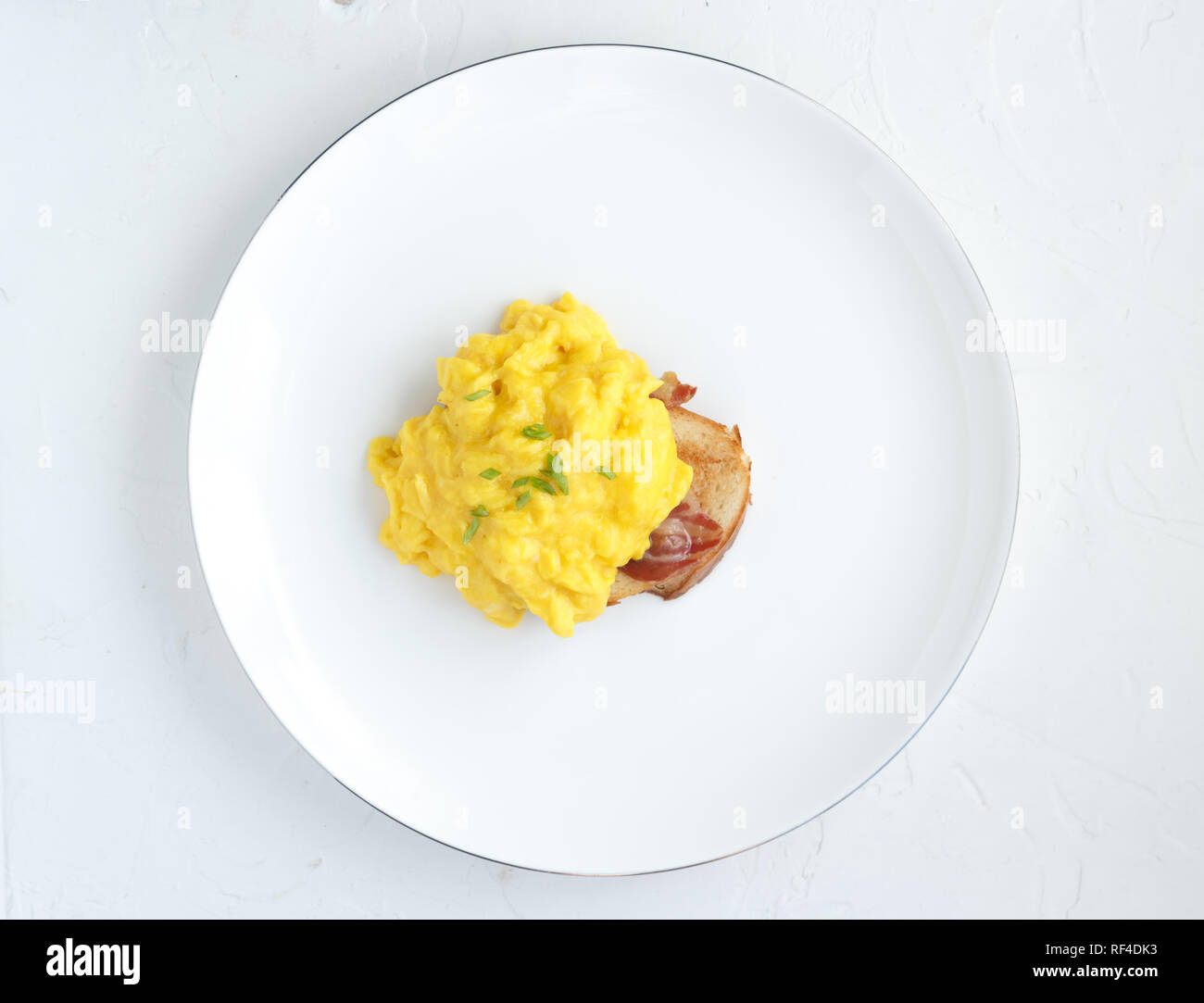 Scrambled eggs on plate over white stone background. Top view, flat lay Stock Photo