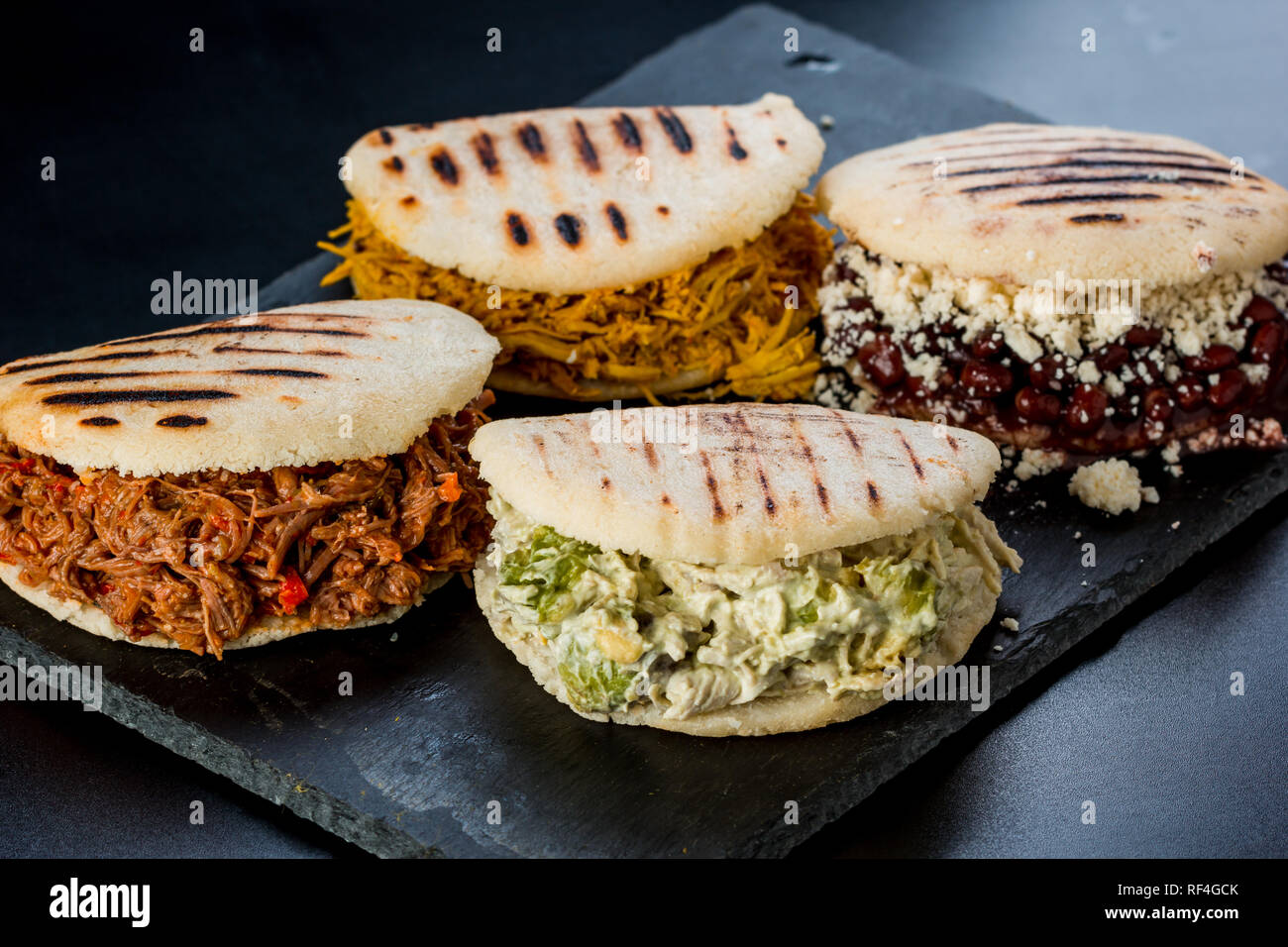 https://c8.alamy.com/comp/RF4GCK/venezuelan-latin-american-food-4-arepas-of-different-stuffing-on-a-black-table-arepa-with-mechada-meat-queen-pepeada-black-beans-with-white-cheese-RF4GCK.jpg