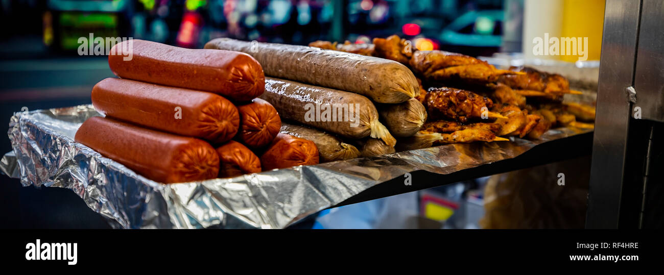 Sausages and a few kebabs sitting on a aluminum foil at a kiosk in New York City. Stock Photo