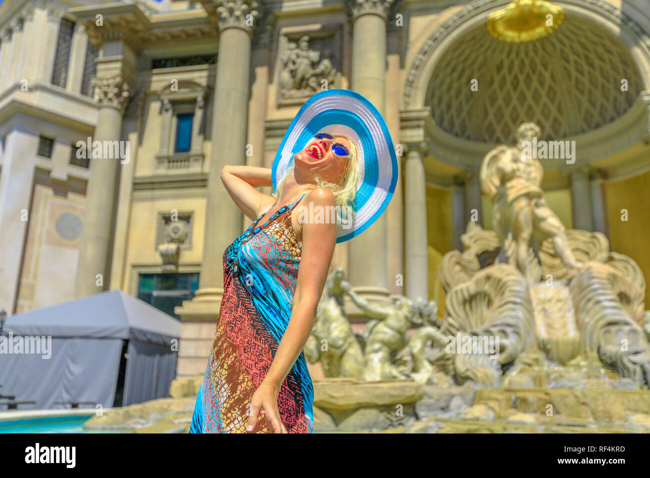 Happy woman with hat enjoying in front of roman empire style facade with columns and statues of popular shopping mall in Las Vegas Strip. Happy lifestyle tourist in Nevada, Unites States. Stock Photo