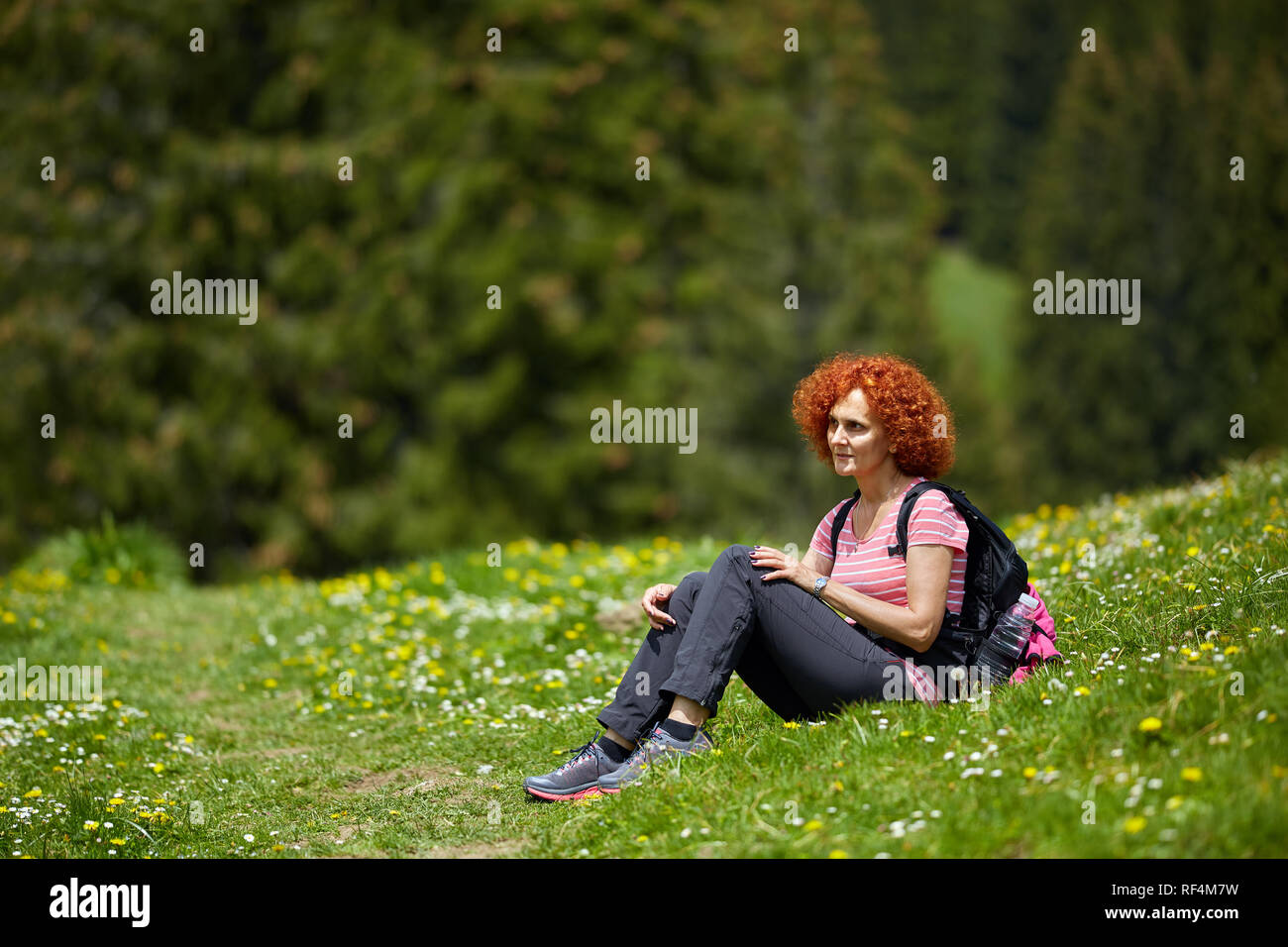 Curly redhead woman with backpack hiking on a trail Stock Photo - Alamy