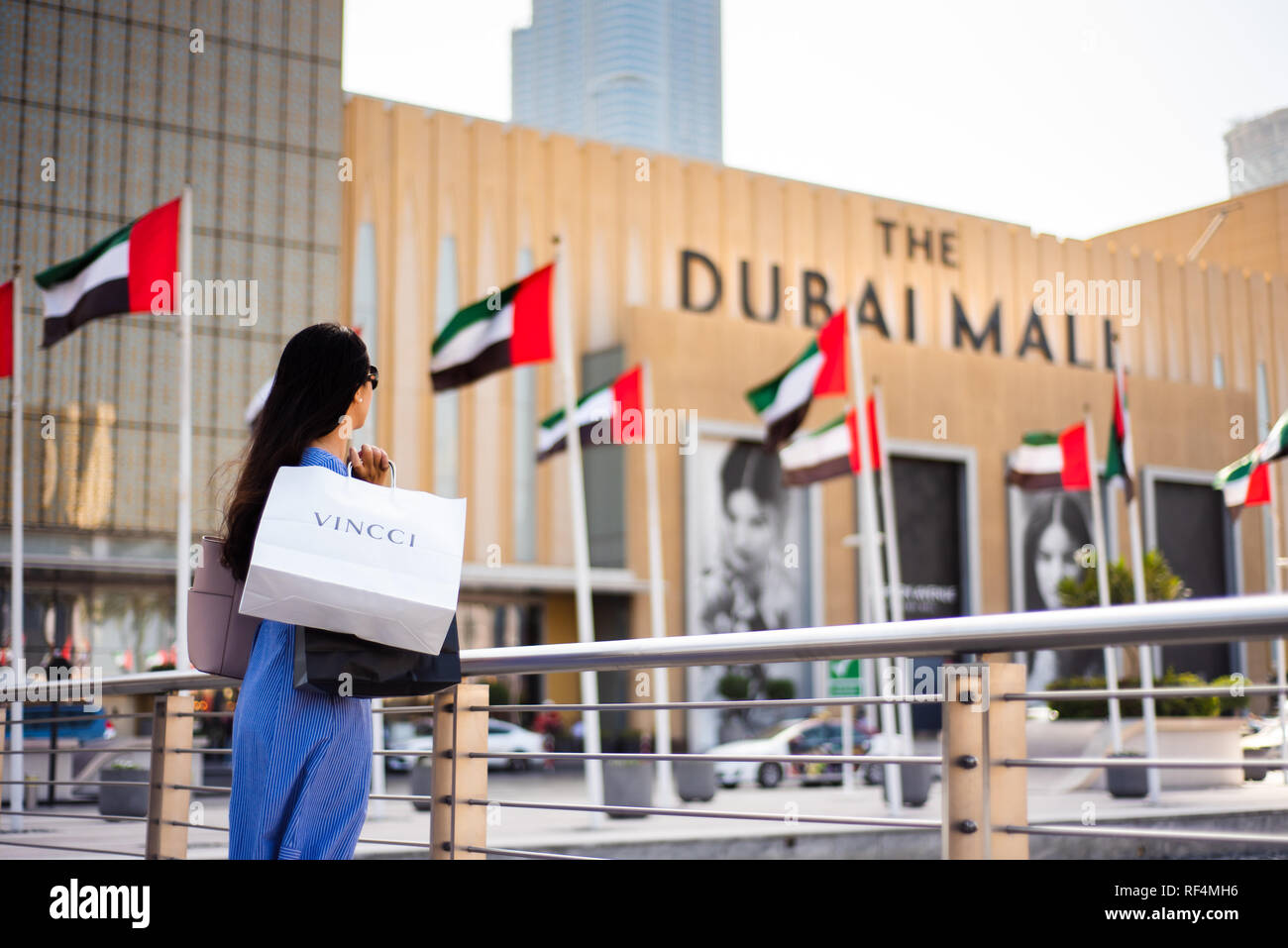 Dubai, United Arab Emirates - March 26, 2018: Asian tourist in front of Dubai mall main entrance with shopping bags Stock Photo