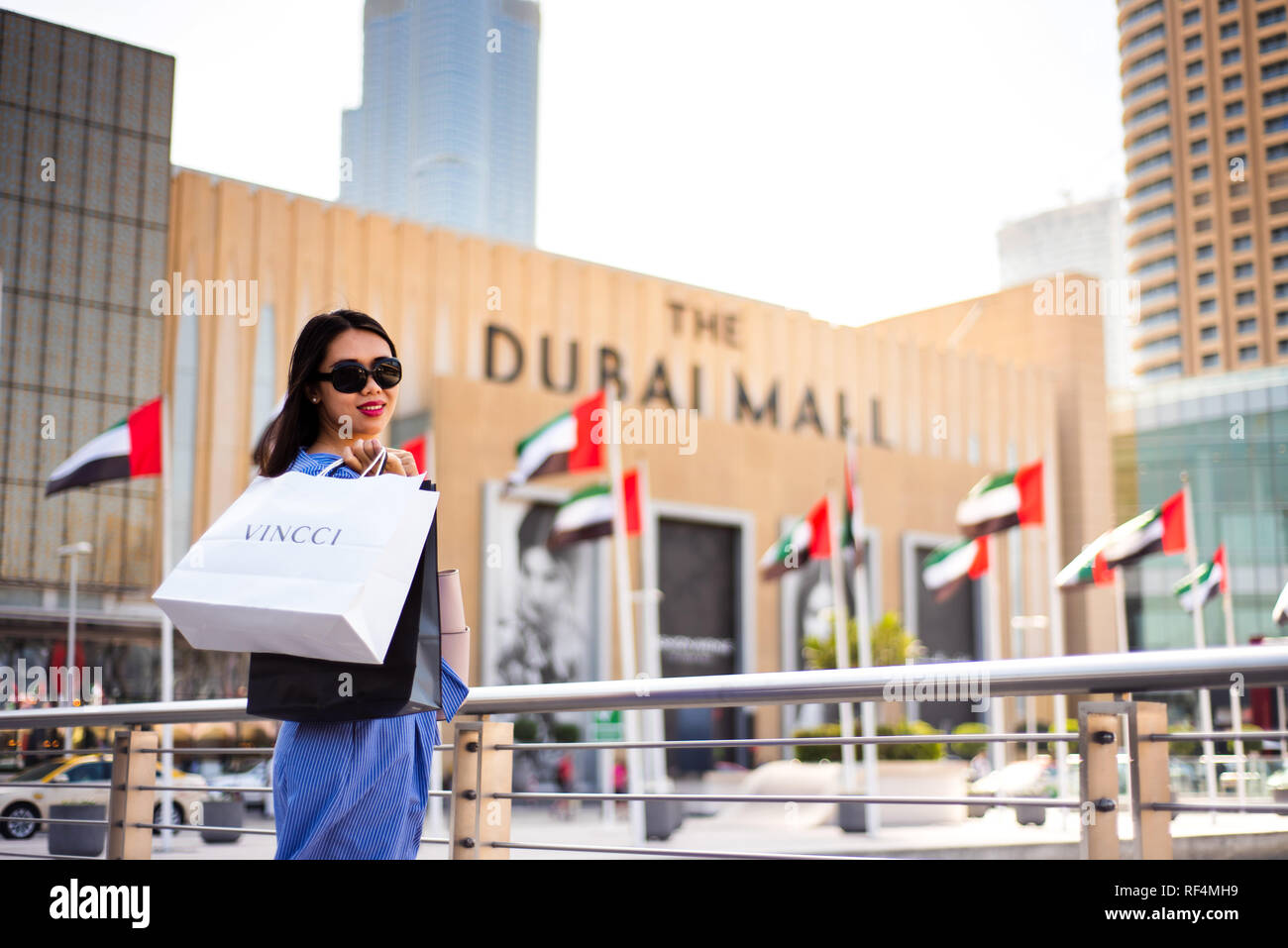 Dubai, United Arab Emirates - March 26, 2018: Asian tourist in front of Dubai mall main entrance with shopping bags Stock Photo