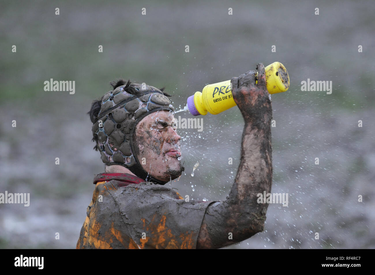 Muddy rugby union player washes face Stock Photo
