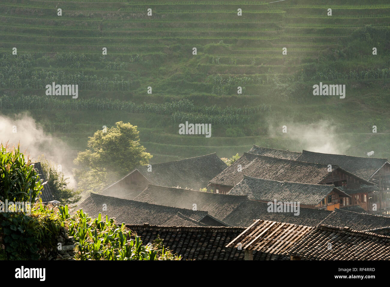 Rooftops and smoke in rice terraces landscape China Stock Photo