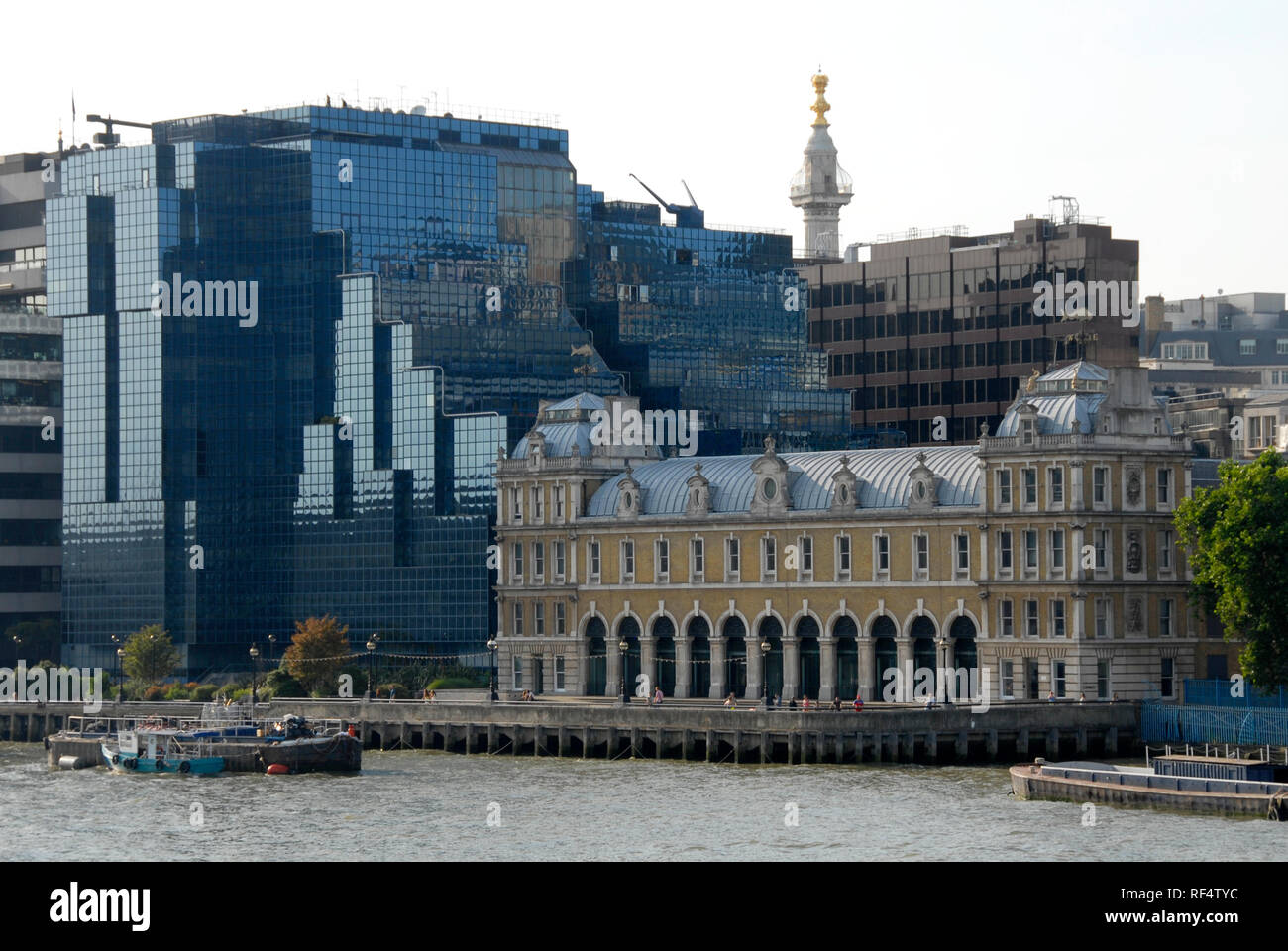 Old Billingsgate fish market building, London, England, surrounded by modern, mainly glass-fronted buildings and the Monument in the background. Stock Photo