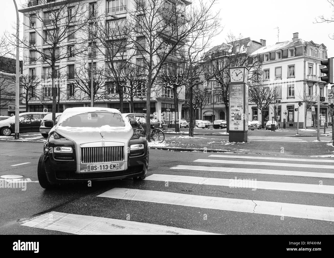STRASBOURG, FRANCE - MAR 18, 2018: New Luxury Rolls-Royce limousine black silver car on French Allee de la Robertsau preparing to enter parking on a snowy day - black and white Stock Photo