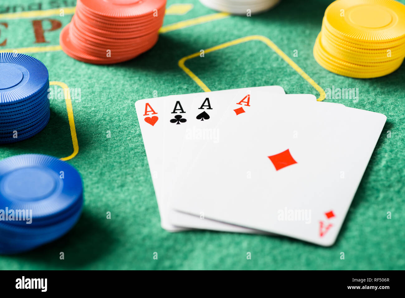 selective focus of green poker table with four aces playing cards and