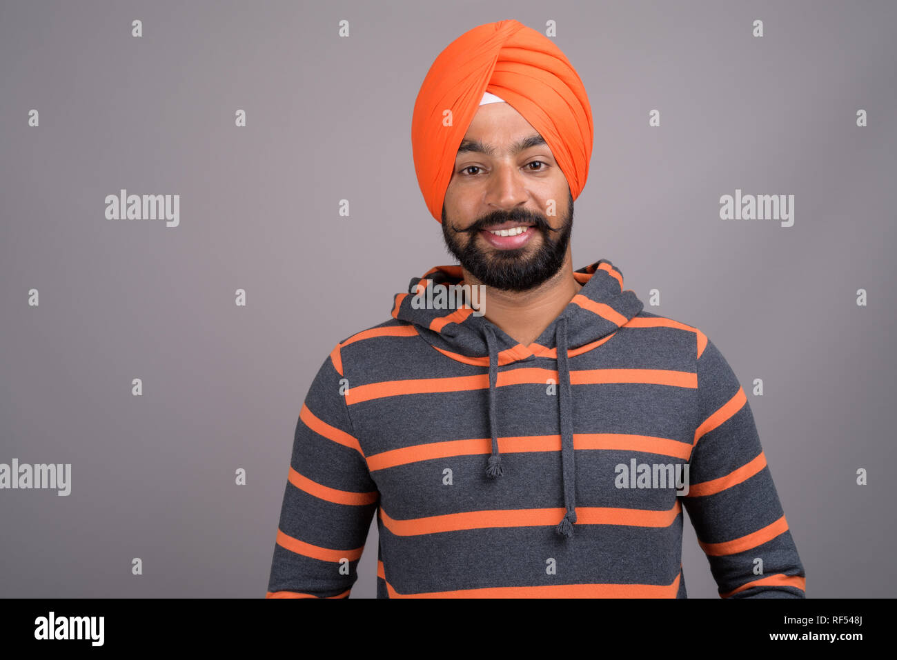 Young handsome Indian Sikh man wearing orange turban Stock Photo