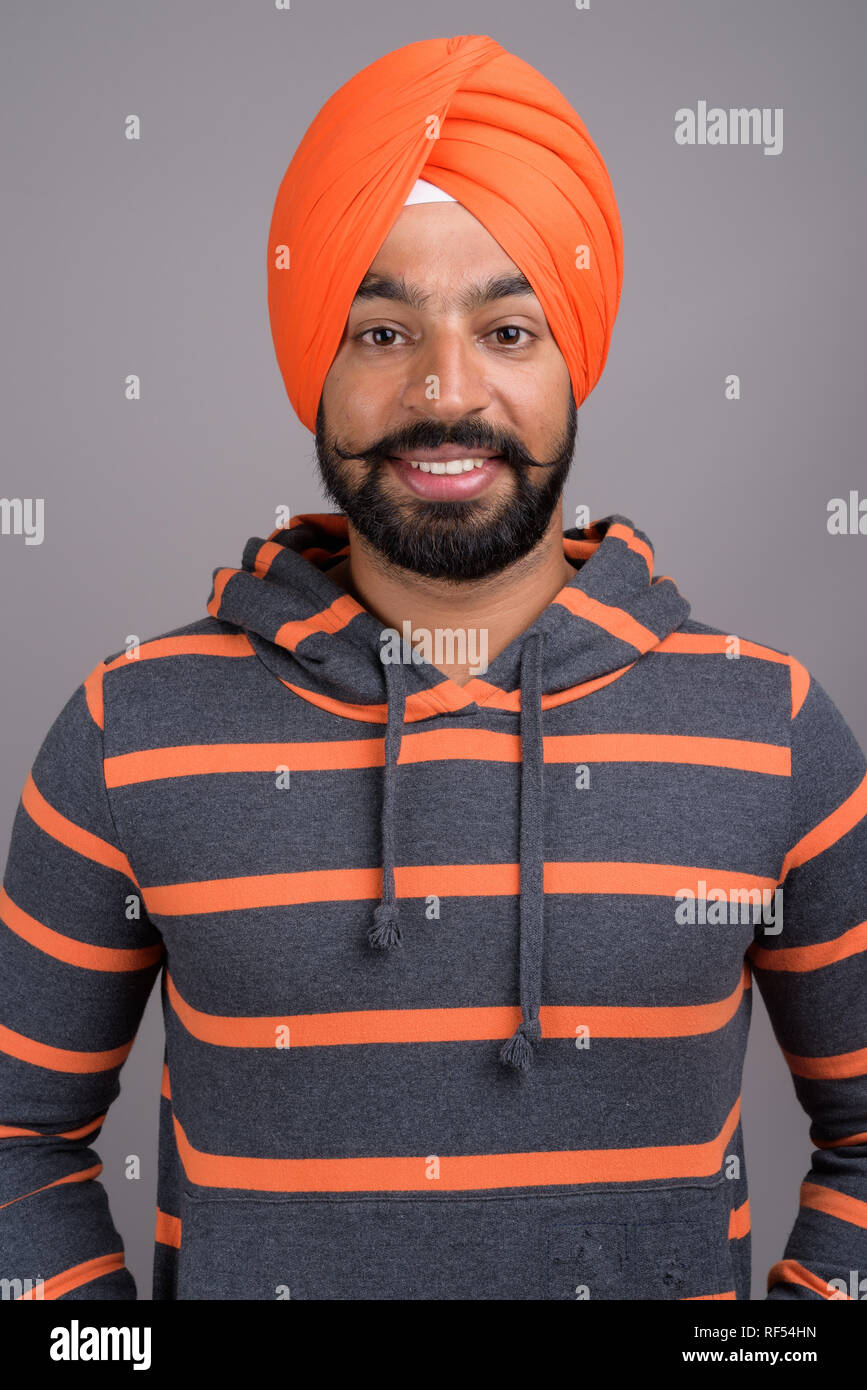 Young handsome Indian Sikh man wearing orange turban Stock Photo