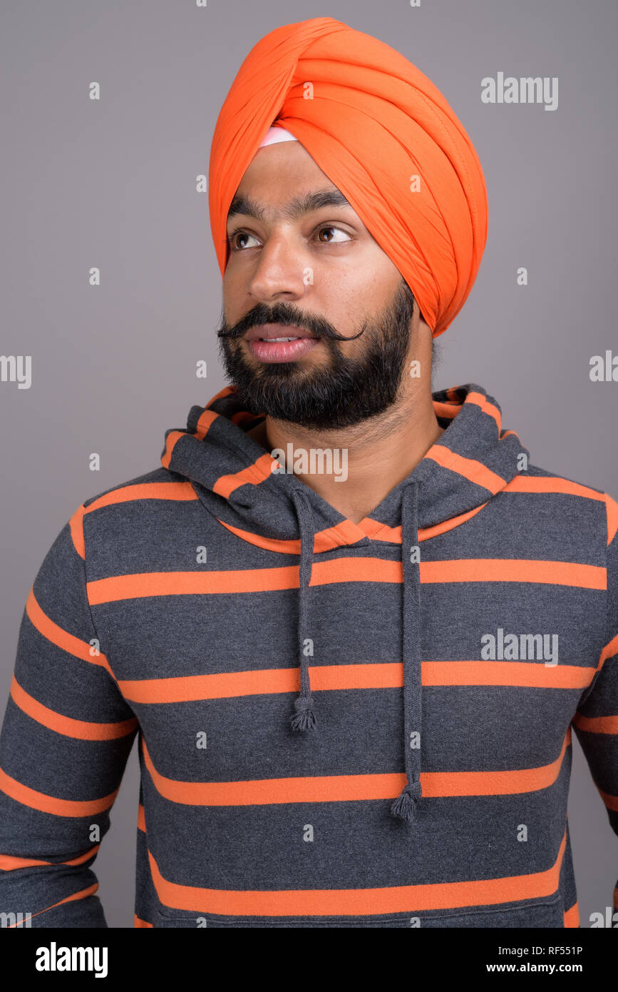 Indian Sikh man wearing orange turban while thinking Stock Photo